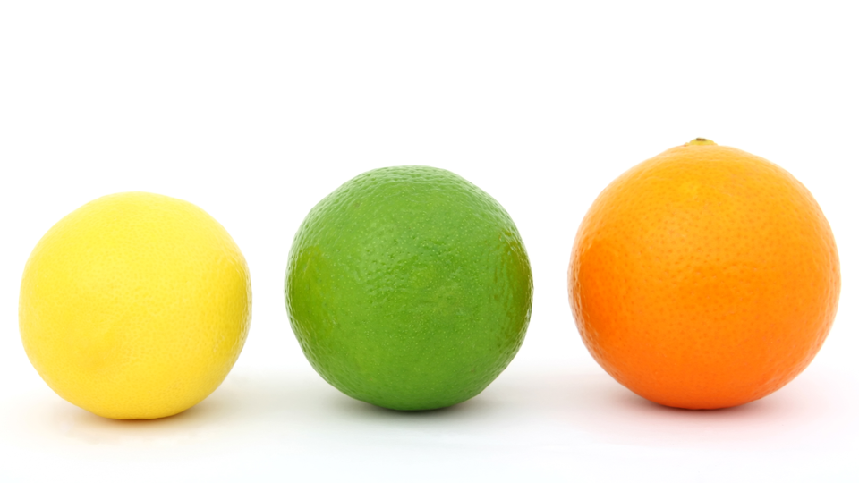 Colorful fruit, a yellow lemon, a green lime and an red coloured orange. Macro closeup, isolated on white, close-up with copyspace
