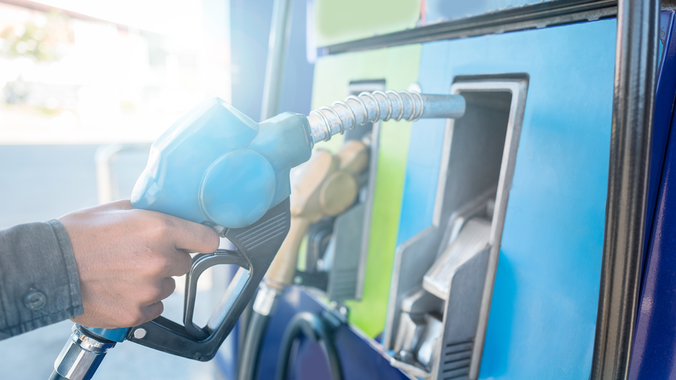 Close up of man's hand holding fuel pump and refueling car in Gas station