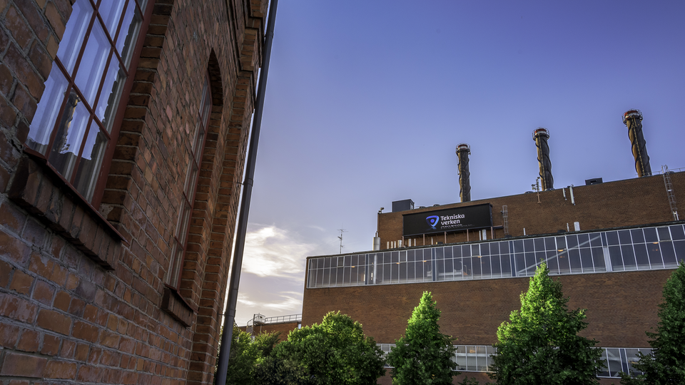 To the right, a modern brick building with three chimneys: a combined heat and power plant. To the left, an older brick building.