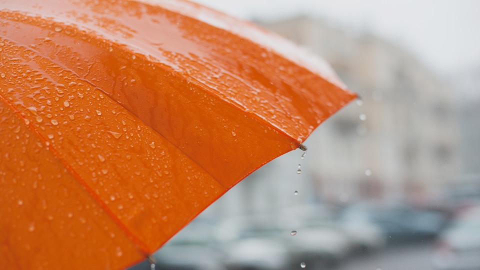 rain drops falling from a bright orange umbrella