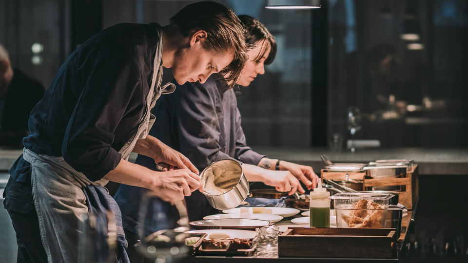 A man and a woman working in the kitchen of a restaurant