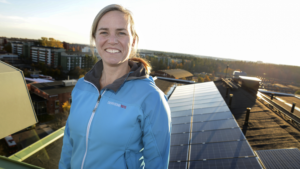 A woman standing on a roof in front of solar cells
