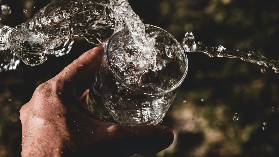 Hand håller glas som fylls med vatten