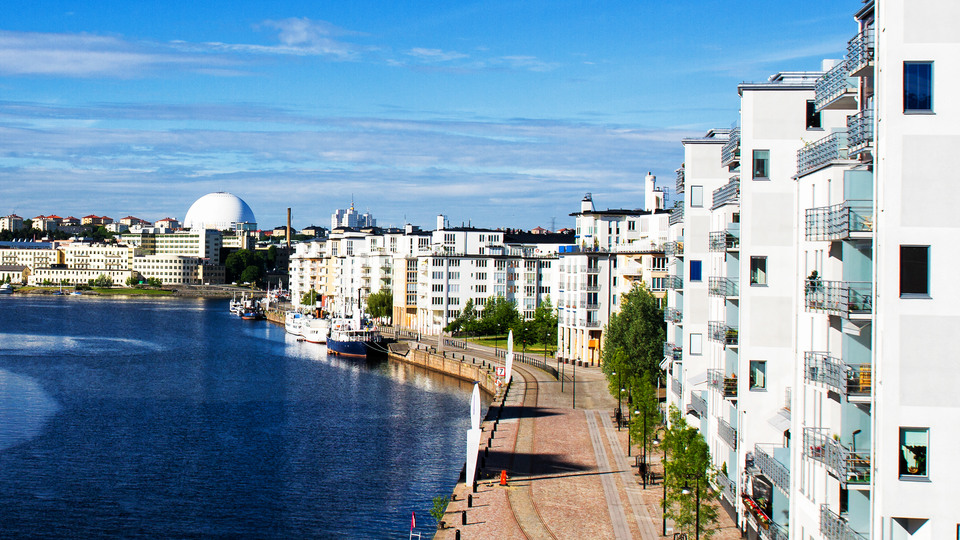 New and modern settlement in Stockholm, Sweden.  Big white apartment complex right by the water, a view of Globen in the distance.