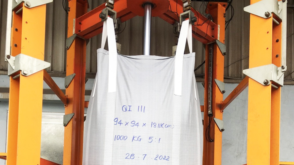 A white bigbag with handwritten text on it, hanging in a construcuction to test its strength.