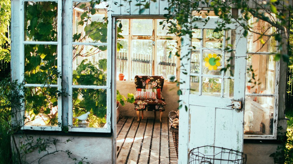 Gammalt växthus med växter och möbler